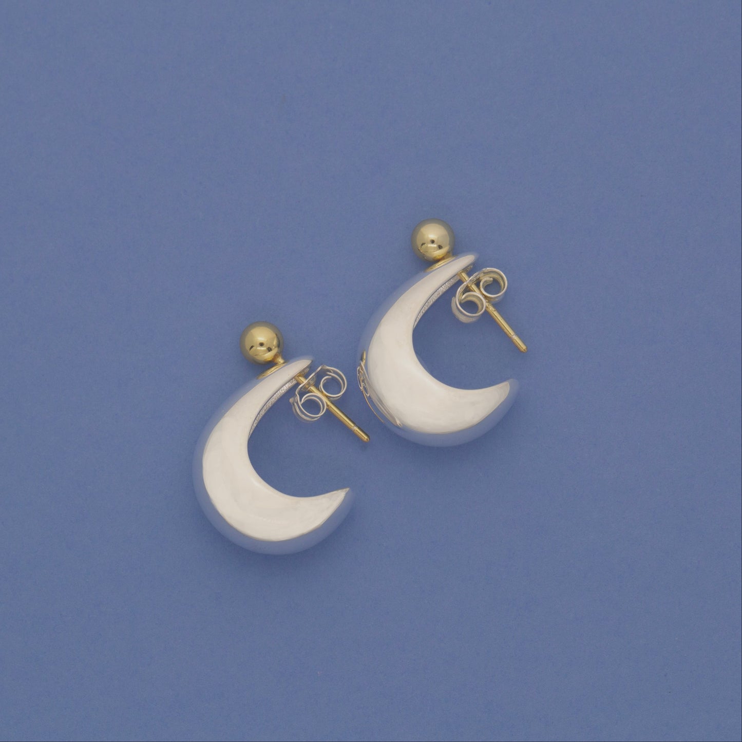 Sterling silver silver and gold half hoop earrings.
