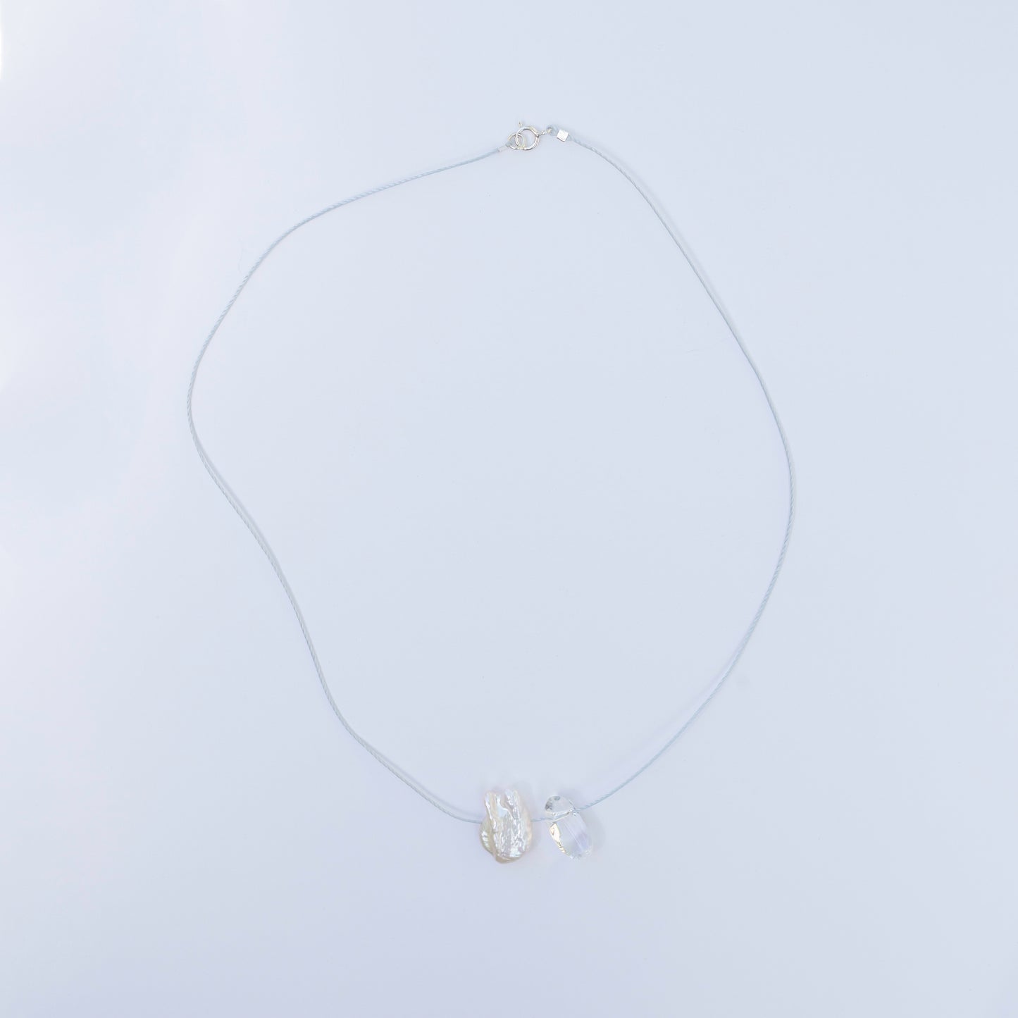 Delicate crystal quartz and baroque pearl necklace on light blue cord with sterling silver clasp.