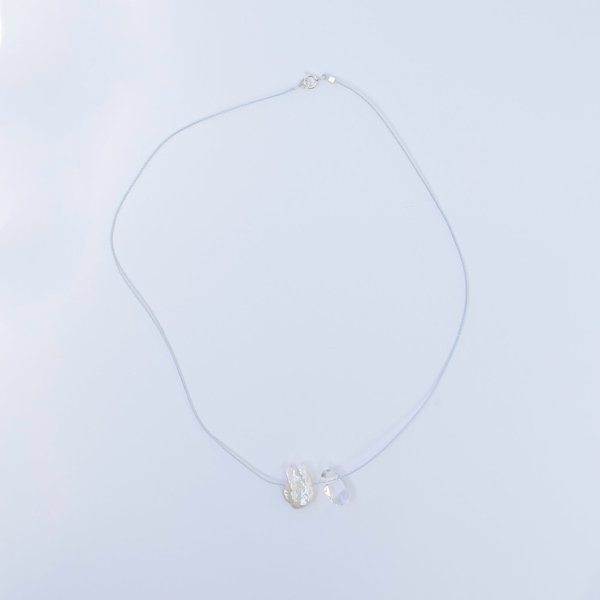 Delicate crystal quartz and baroque pearl necklace on light blue cord with sterling silver clasp.